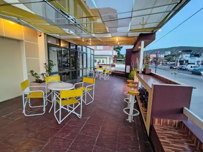 a patio with yellow chairs and tables on a building at Apart Hotel RITZ in Villa Carlos Paz