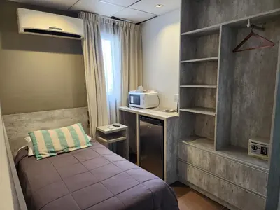 a small bedroom with a bed and a microwave at PH suites in Río Cuarto