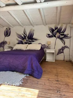 a bedroom with a purple bed with flowers on the wall at Indra-La Casa de Nanda in San Javier