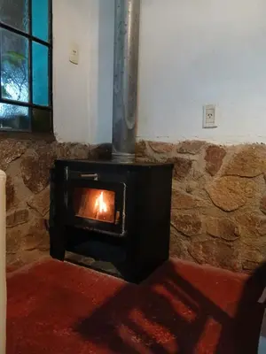 a wood stove in a room with a stone wall at Indra-La Casa de Nanda in San Javier
