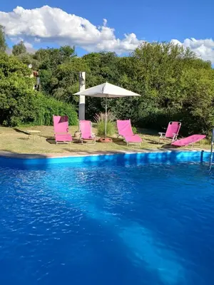 a group of pink chairs and an umbrella next to a swimming pool at Indra-La Casa de Nanda in San Javier