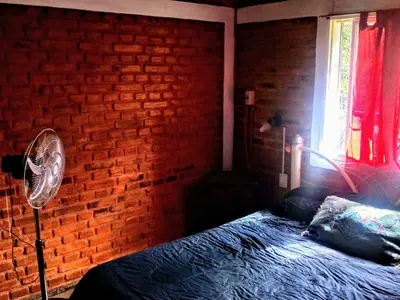 a bedroom with a brick wall and a bed with a fan at El Faro in Potrero de Garay