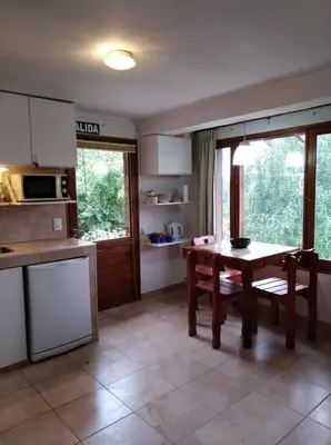 a kitchen with a wooden table and a table and chairs at VISTA FRANCA in La Cumbrecita