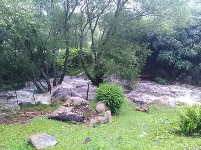 a garden with rocks and trees and a river at VISTA FRANCA in La Cumbrecita