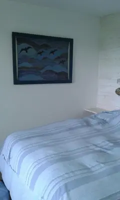 a bedroom with a bed with a painting on the wall at VISTA FRANCA in La Cumbrecita