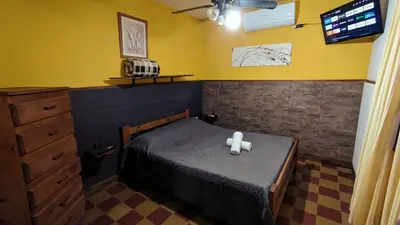 a small bedroom with a bed and a tv at Benvinguts Casa y Apartamentos de 1 a 12 personas Pleno Centro Santa Rosa de Calamuchita in Santa Rosa de Calamuchita