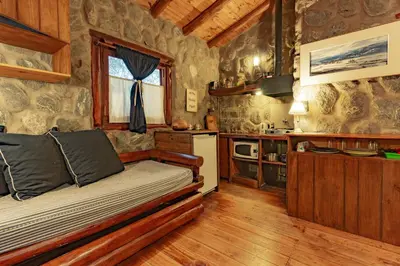 a bedroom with a bed and a kitchen in a cabin at ASM CABAÑAS XIII in Merlo