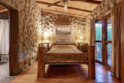 a bedroom with a bed in a stone wall at ASM CABAÑAS XIII in Merlo