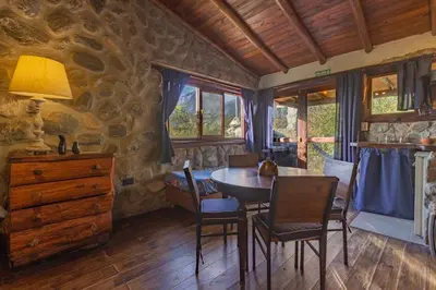 a dining room with a table and chairs and a stone wall at ASM CABAÑAS XIII in Merlo