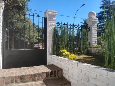a black gate with a stone wall and a fence at CERRO CHICO APART in Cordoba