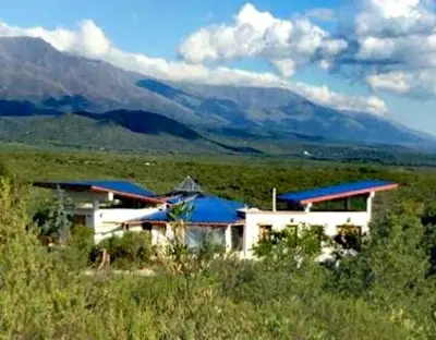 a building with blue roofs with mountains in the background at Refugio: El Llamado in Villa de Las Rosas