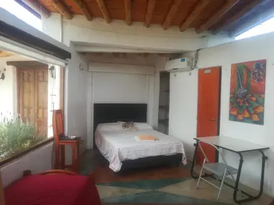a small bedroom with a bed and a table at Refugio: El Llamado in Villa de Las Rosas