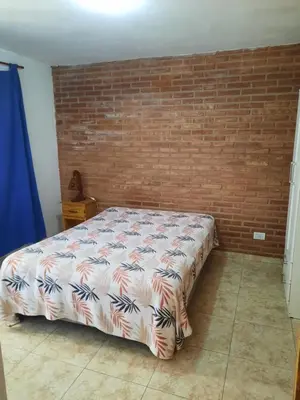 a bed in a room with a brick wall at Departamentos Mina Clavero in Mina Clavero