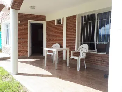 two white chairs and a table on a porch at Departamentos Mina Clavero in Mina Clavero
