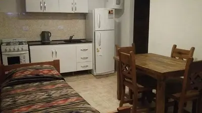 a kitchen with a table and a white refrigerator at Departamentos Mina Clavero in Mina Clavero