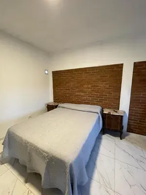 a bedroom with a bed and a brick wall at Departamentos Mina Clavero in Mina Clavero