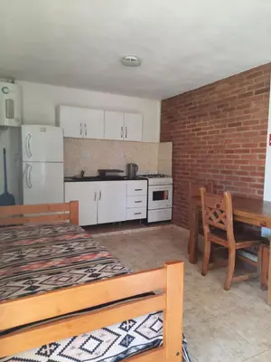 a kitchen with a bed and a table and a brick wall at Departamentos Mina Clavero in Mina Clavero