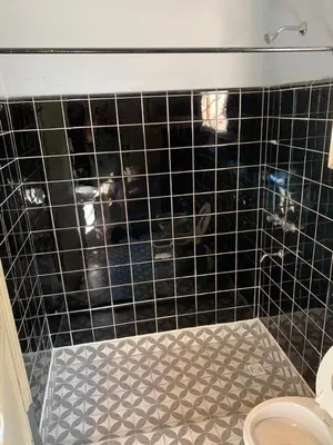 a bathroom with a black tiled wall and a toilet at Casa de Montaña in Cordoba