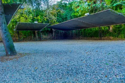 a large gravel parking lot with a shade tree at Hotel Villa Sol in Merlo