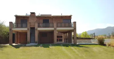 a large brick house with a balcony on a yard at Mardi - Departamentos de alquiler temporario in Bialet Massé