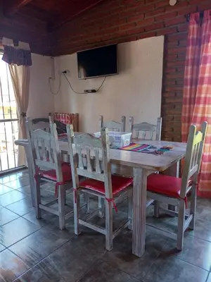 a wooden table with chairs and a television on a wall at Mardi - Departamentos de alquiler temporario in Bialet Massé