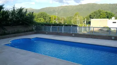 a blue swimming pool with mountains in the background at Mardi - Departamentos de alquiler temporario in Bialet Massé