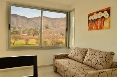 a living room with a couch and a large window at Los Cóndores Aparts. in Villa General Belgrano