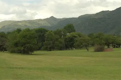 a field with trees and mountains in the background at Los Cóndores Aparts. in Villa General Belgrano