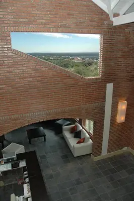 a room with a brick wall with a couch and a window at La Barraca Resort in Merlo