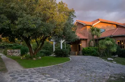 a house with a tree and a gravel driveway at La Barraca Resort in Merlo