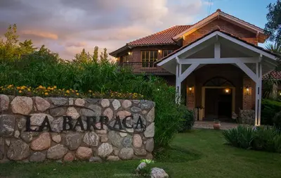 a house with a stone wall in front of it at La Barraca Resort in Merlo