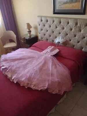 a bed with a red comforter and a white dress on it at Casa Alberdi in Cordoba