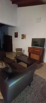 a living room with a couch and a table and a television at La Casa de Elisa in Santa Rosa de Calamuchita