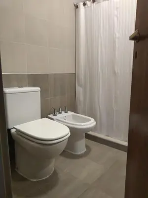 a bathroom with a white toilet and a sink at Apartamentos Anahí in Villa Parque Siquiman