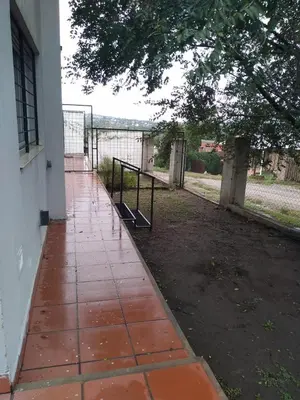 a walkway next to a building with a fence at Apartamentos Anahí in Villa Parque Siquiman