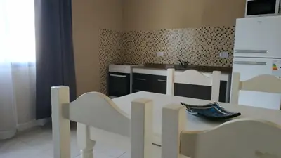 a kitchen with a white table and chairs and a white refrigerator at Ayres de Merlo Aparts in Merlo