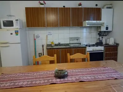 a kitchen with a wooden table and a kitchen with a refrigerator at Apartamentos Santa Rosa PB 1 in Cordoba