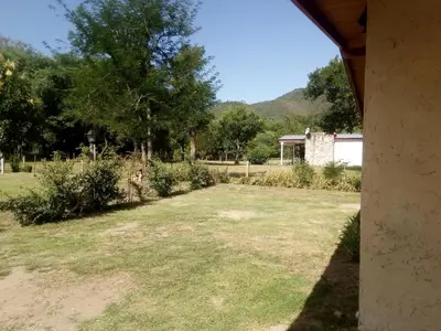 a large yard with grass and trees and a house at El Amanecer in Santa Rosa de Calamuchita