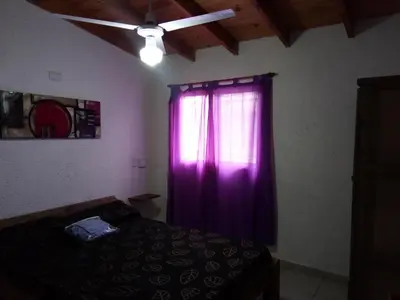 a bedroom with a purple curtain and a window at El Amanecer in Santa Rosa de Calamuchita