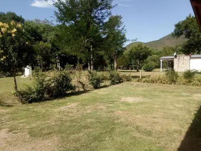 a yard with grass and trees and a building at El Amanecer in Santa Rosa de Calamuchita