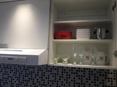 a kitchen cabinet with wine glasses and a microwave at Departamento Torre Sofitel in Río Cuarto