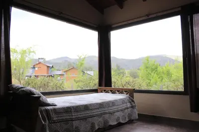 a bedroom with a bed and large windows with mountains at Postal de las Sierras in Santa Rosa de Calamuchita