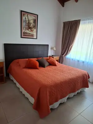 a bedroom with a large bed with an orange blanket at Le Bel-Edén in Villa General Belgrano