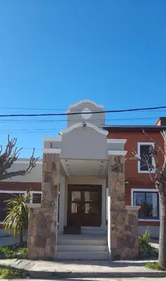 a brick house with a front door and a tree at Residencial Sol del Champaqui in Mina Clavero