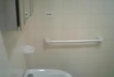 a bathroom with a white urinal and a shelf on the wall at Dptos LOW COST in Mina Clavero