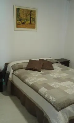 a bed in a bedroom with a picture on the wall at Tu Casa en Villa General Belgrano Calamuchita Córdoba in Villa General Belgrano
