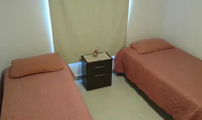 a room with two beds and a table with a clock on it at Tu Casa en Villa General Belgrano Calamuchita Córdoba in Villa General Belgrano