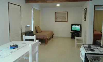a living room with a couch and a bed and a television at Tu Casa en Villa General Belgrano Calamuchita Córdoba in Villa General Belgrano