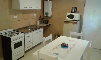 a kitchen with a table and a stove and a microwave at Tu Casa en Villa General Belgrano Calamuchita Córdoba in Villa General Belgrano