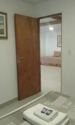 a door to a bedroom with a bed and a mirror at Tu Casa en Villa General Belgrano Calamuchita Córdoba in Villa General Belgrano